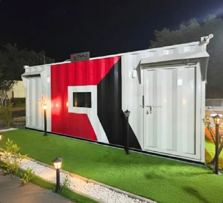 Quad Cabins branded VIP cabin lit at night on landscaped grounds